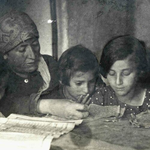 Kacyzne 84 Laskarzew 1920s A group of young girls sitting around a table reading with their woman teacher in a girls Kheyder also AB Genera 4b 2022 03 18 165831 voew 2022 03 18 170103 nvua