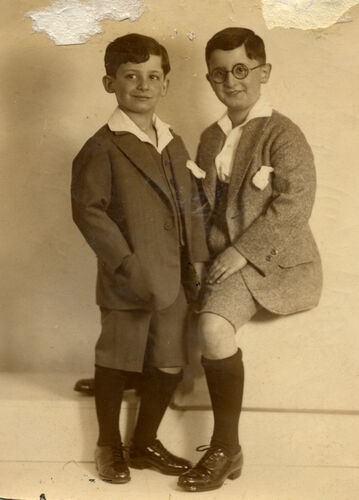 Deux garçons près du même âge, posent côte à côte. Élégamment vêtus, ils esquissent de timides sourires.