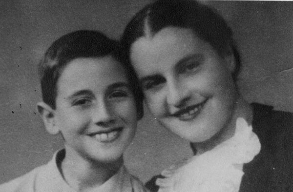 A close-up of the faces of a young boy and a woman smiling at the camera, heads bent towards each other, touching.