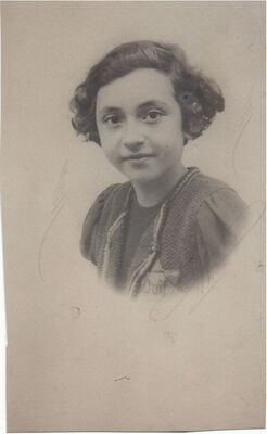 Head and shoulders of a child gazing at the camera with a slight smile, most of a Star of David with French writing on it visible on the front of her clothing.