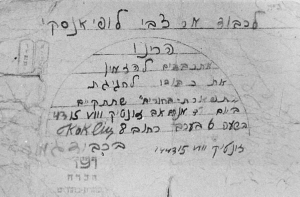 A paper containing Hebrew writing and faded stamps featuring Hebrew letters.