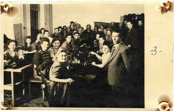 A group of people posing around sewing machines, looking at the camera.