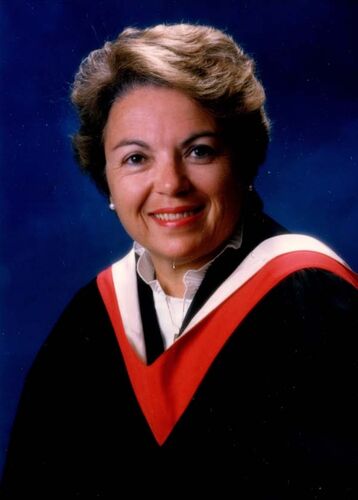 Graduation photo of woman wearing a graduation gown and smiling at the camera.