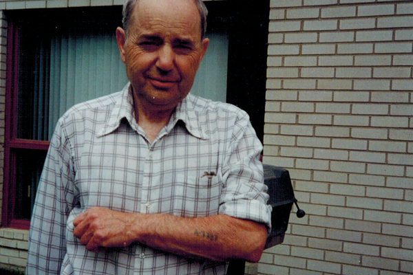 Henry Friedman displaying his tattoo number, A-7727, in front of his house. Toronto, 1984.