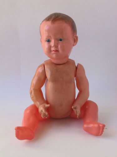 A plastic doll with realistic features and no clothing sitting against a light background.