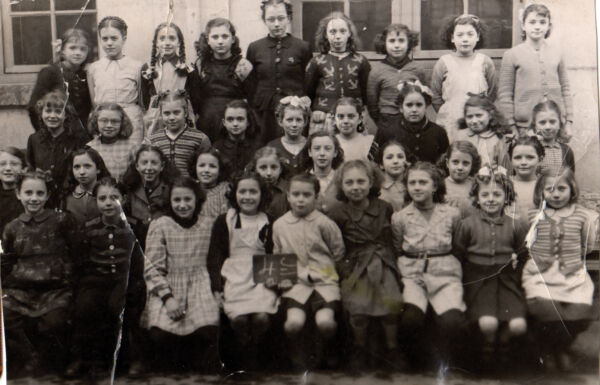 Une trentaine de fillettes sont installées devant un bâtiment pour la photo de classe.