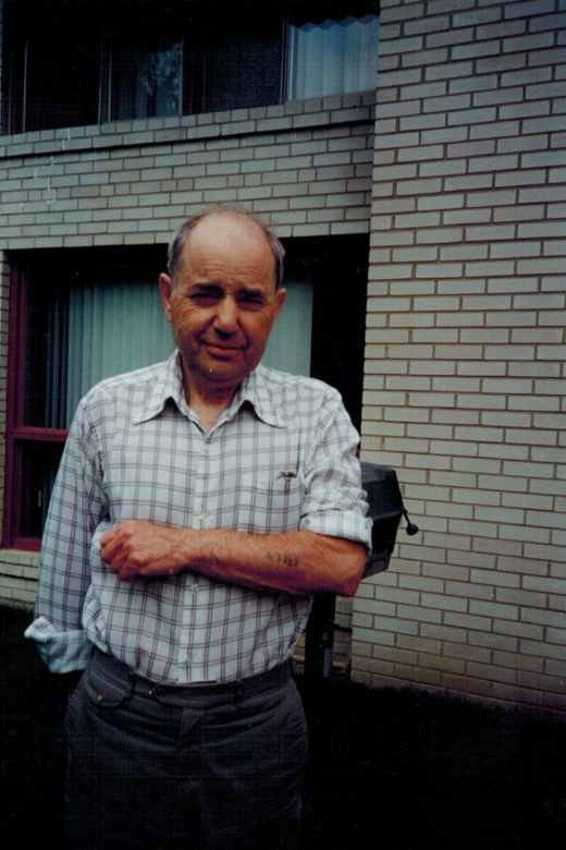 Henry Friedman displaying his tattoo number, A-7727, in front of his house. Toronto, 1984.