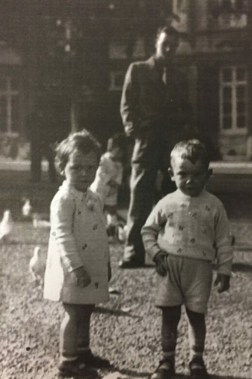 
Reny (left), and her twin brother, Leo, age two or three, feeding pigeons on Vrijthof Street. Reny’s uncle Siegfried is in the background. Maastricht, the Netherlands, circa 1939–1940.
